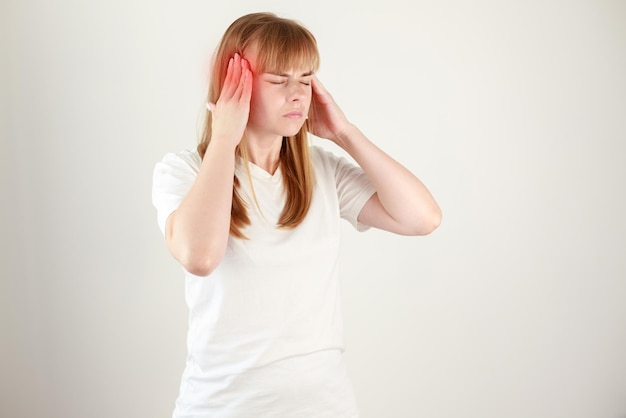 Woman holding her hands to the head in pain Young woman having severe headaches from migraines