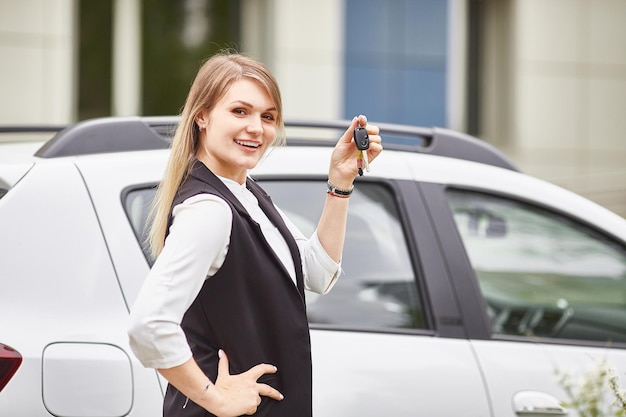 Woman holding keys to new car auto and smiling at camera