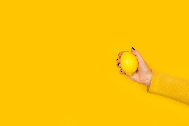 Woman holding a lemon on a yellow background