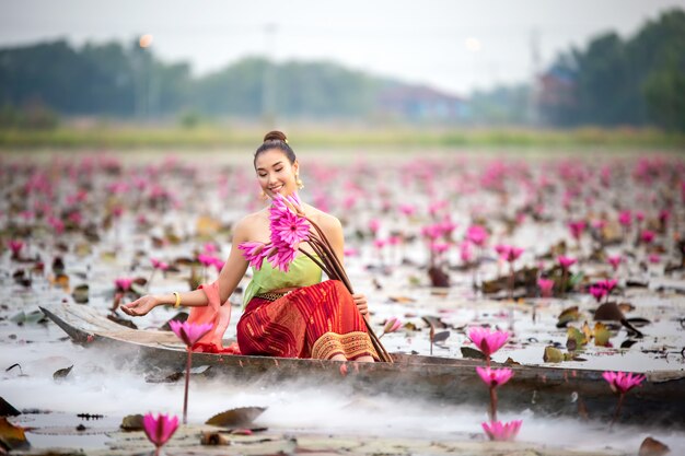 Woman Holding Lotus While Sitting On Boat In Lake