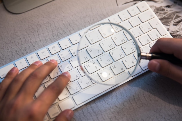 Woman holding magnifier and working computer