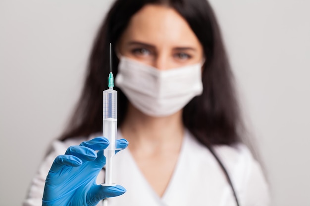 Woman holding medical injection syringe in her outstretched hand towards the camera