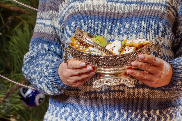 Woman holding metal vase with gingerbread cookies