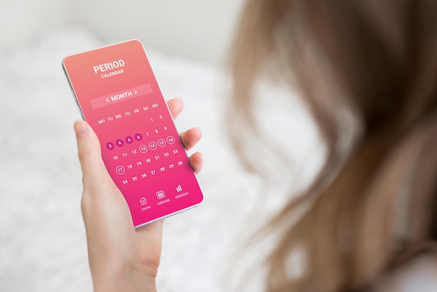 Woman holding a mobile phone with a menstrual cycle calendar application