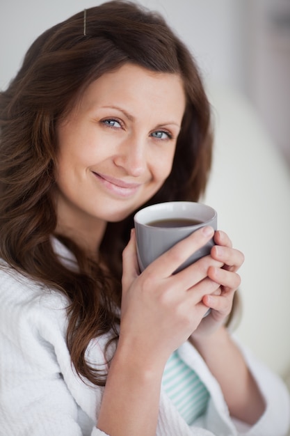 Woman holding a mug of coffee while looking at camera