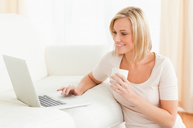 Woman holding a mug while using a laptop