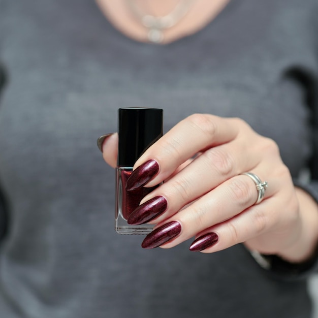 Photo a woman holding a nail polish with a red nail polish