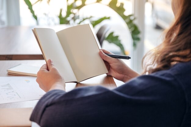 woman holding and opening a blank notebook on wooden table