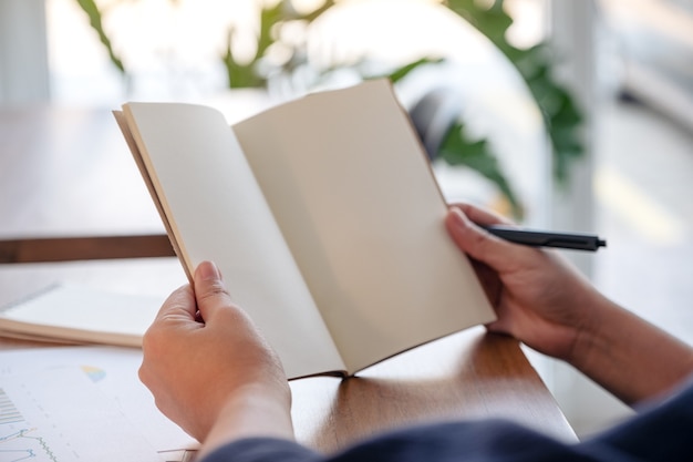 woman holding and opening a blank notebook on wooden table