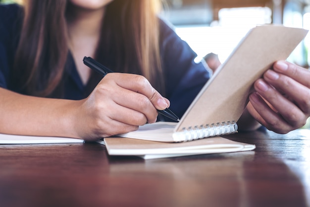 Woman holding and opening a blank notebook to write on wooden table