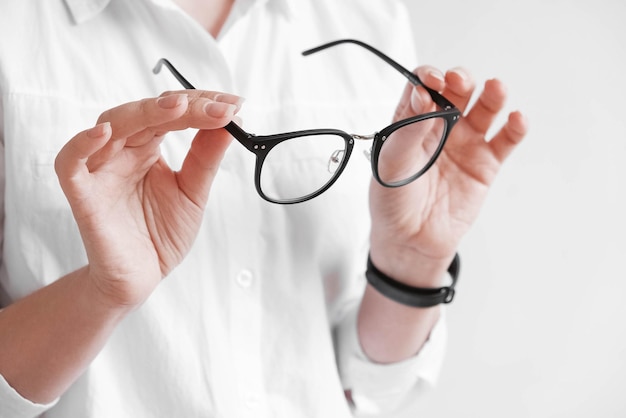 Photo woman holding optical glasses in a black frame on a white background. copy, empty space