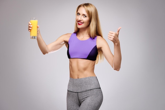 Woman holding an orange juice and showing her thumb up The concept of a healthy diet