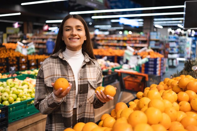 Woman holding oranges in fruit section of supermarket