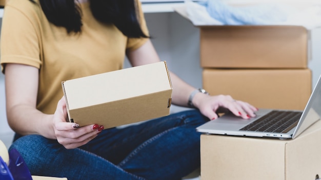 Woman holding parcel boxes and using laptop, Selling products online,Delivering parcels.