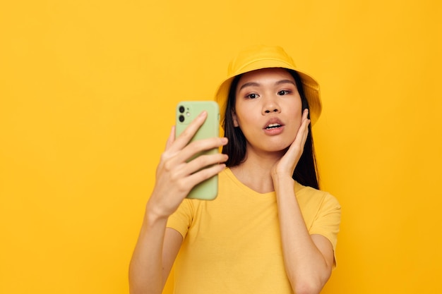 Woman holding a phone posing lifestyle technology yellow background unaltered