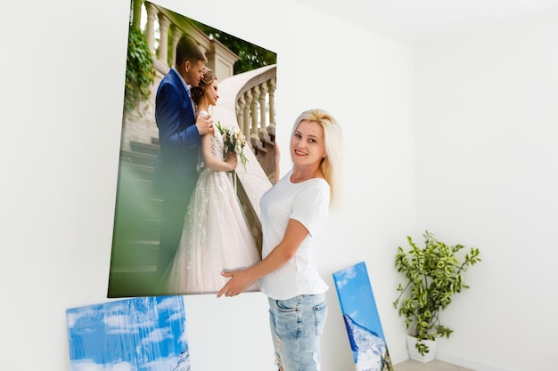 woman holding photo canvas on the background of a interior.