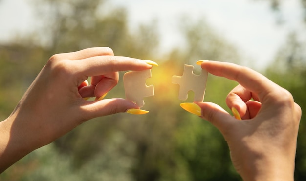 Woman holding a piece of wooden jigsaw puzzle together in the outdoors