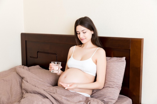 woman holding pill and glass of fresh pure water Healthy millennial women taking antioxidant medicine vitamins healthcare concept