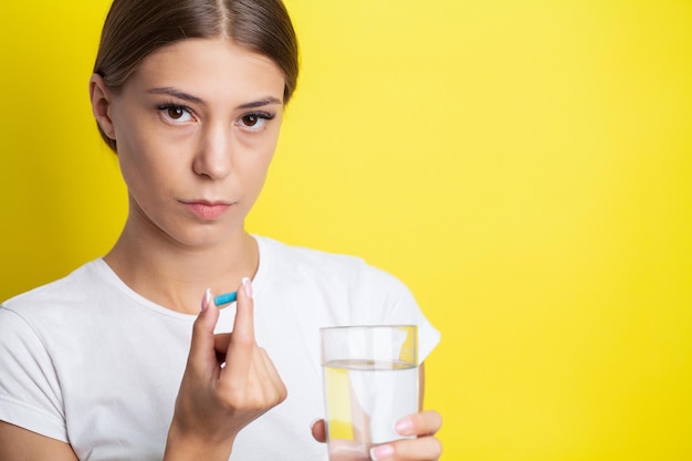 Woman holding pill and glass of water taking dietary supplements