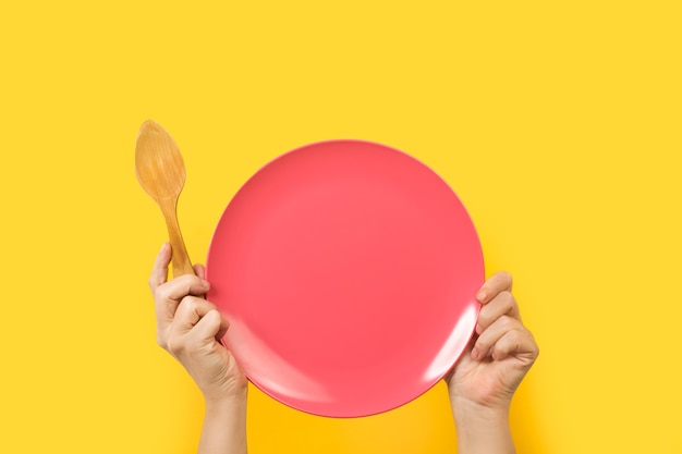 Woman holding a pink plate with both hands on a yellow