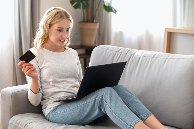 Photo woman holding plastic credit card using laptop pay bills online