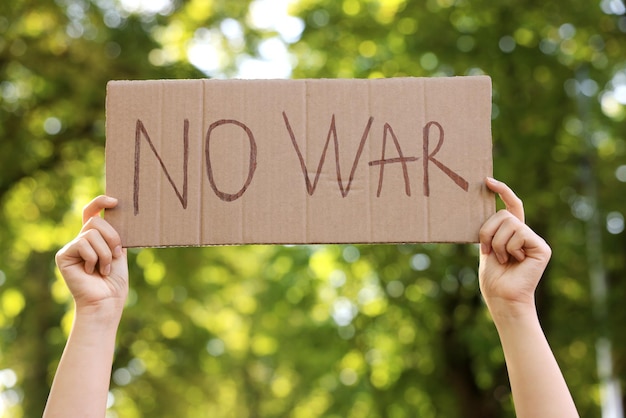 Woman holding poster with words No War in park closeup