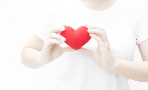 Woman holding and protecting a red heart shape on white background closeupSymbol of love or dating Valentines day