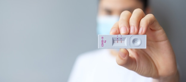 Woman holding Rapid Antigen Test kit with Positive result during swab COVID-19 testing. Coronavirus Self nasal or Home test, Lockdown and Home Isolation concept