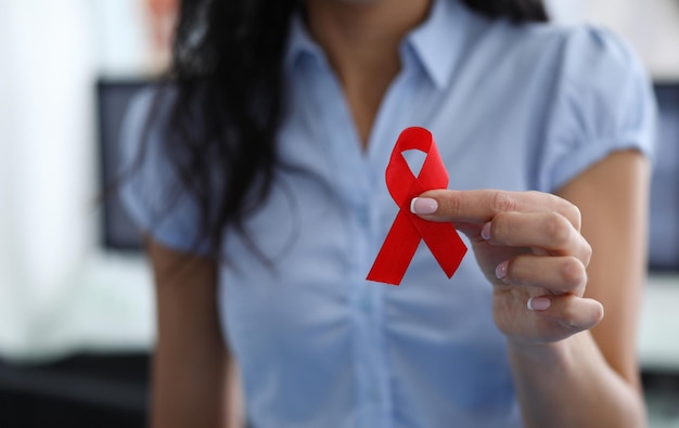 Woman holding red ribbon symbol in her hand