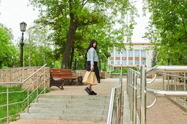 Woman holding several paper bags walking outdoors in the park