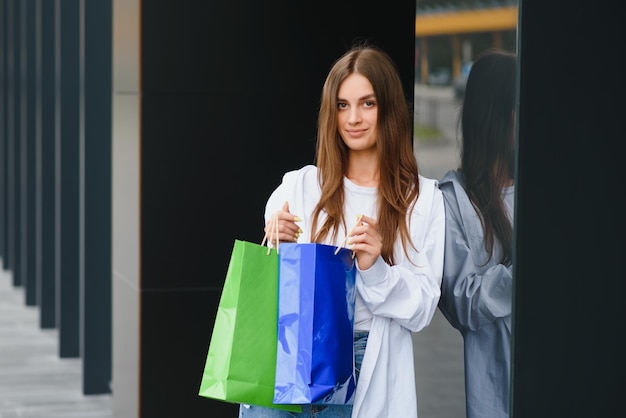 Woman holding shopping bags of luxury brands walking near shopping mall