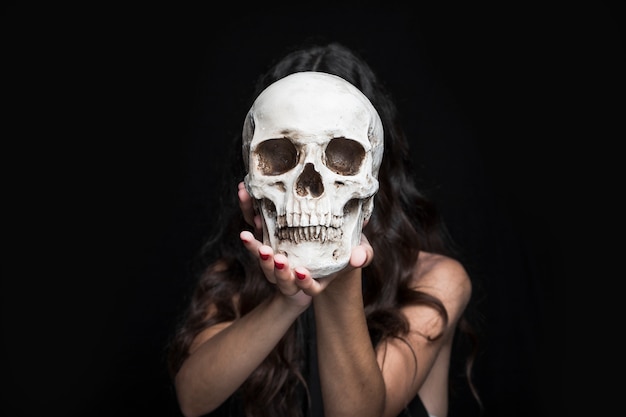 Woman holding skull before face 