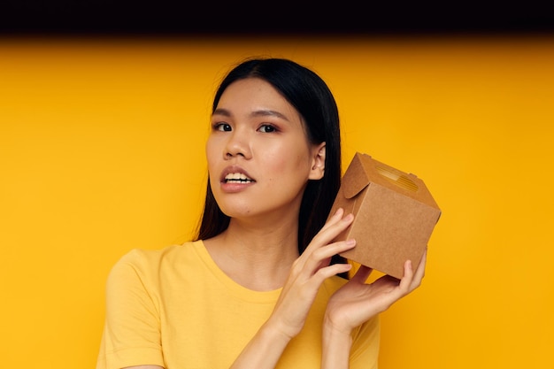 Woman holding a small box gift yellow background