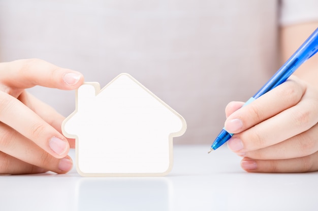 Woman holding the small home with white blank over the document 