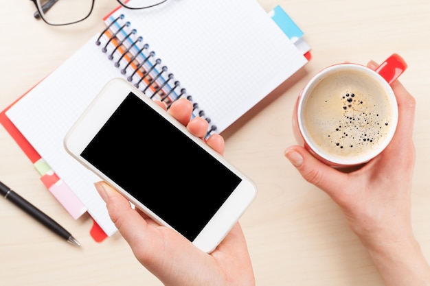 Woman holding smartphone above business desk