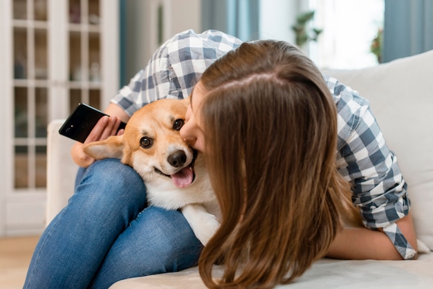 Woman holding smartphone and kissing her dog