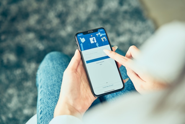 Photo woman holding smartphone and pressing the facebook screen