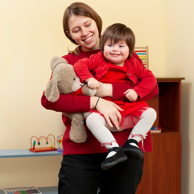 Woman holding smiley child with down syndrome