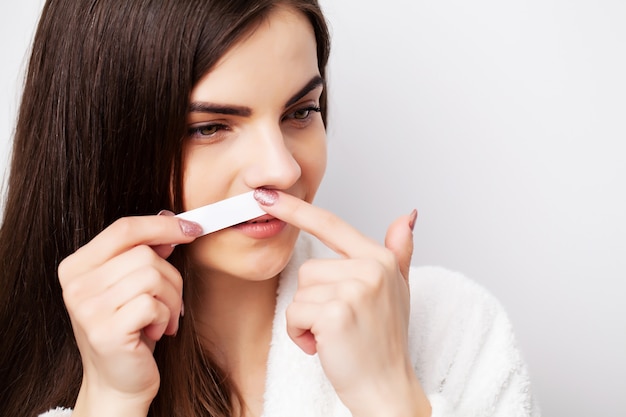 Woman holding stripe with wax to remove facial hair