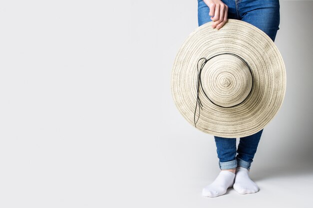 Woman holding a summer hat on a gray background