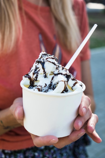 Woman holding takeaway cup with ice cream or frozen yogurt