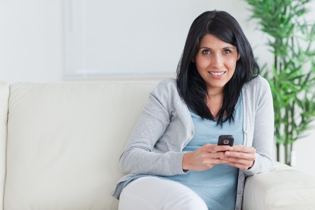 Woman holding a telephone while resting on a couch