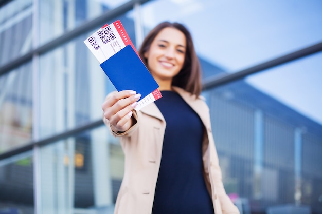 Woman holding two air ticket in abroad passport near airport