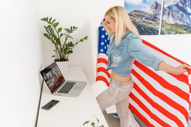 woman holding usa flag and video by laptop.