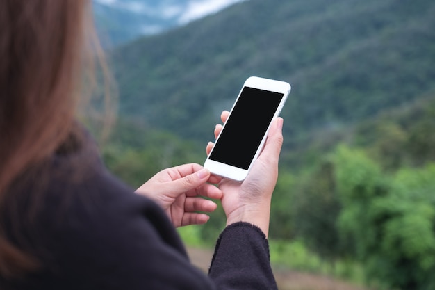 woman holding white smart phone with blank desktop screen in outdoor