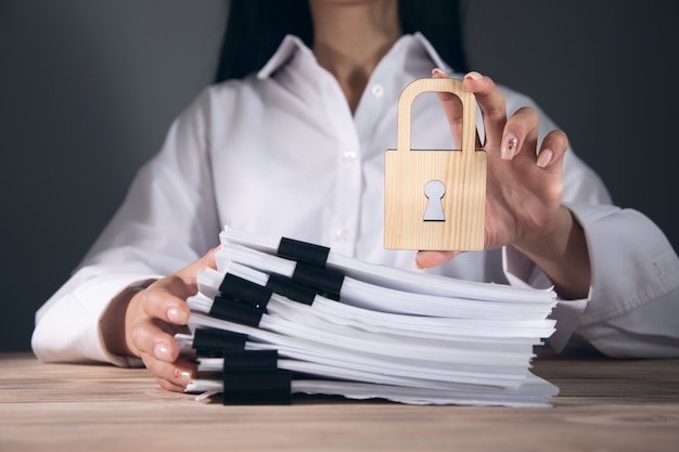 Woman holding wooden lock and documents.