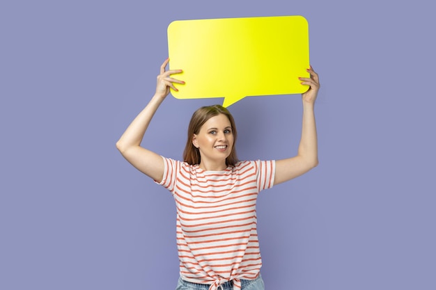 Woman holding yellow bubble for text looking at camera with toothy smile