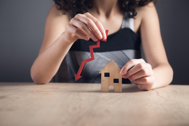 Woman holds an arrow down over model of the house