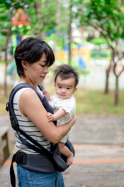 A woman holds a baby in a carrier.