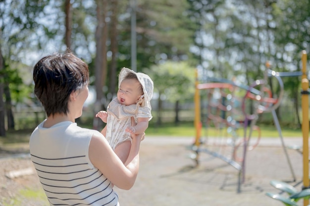 A woman holds a baby in her arms in a park.